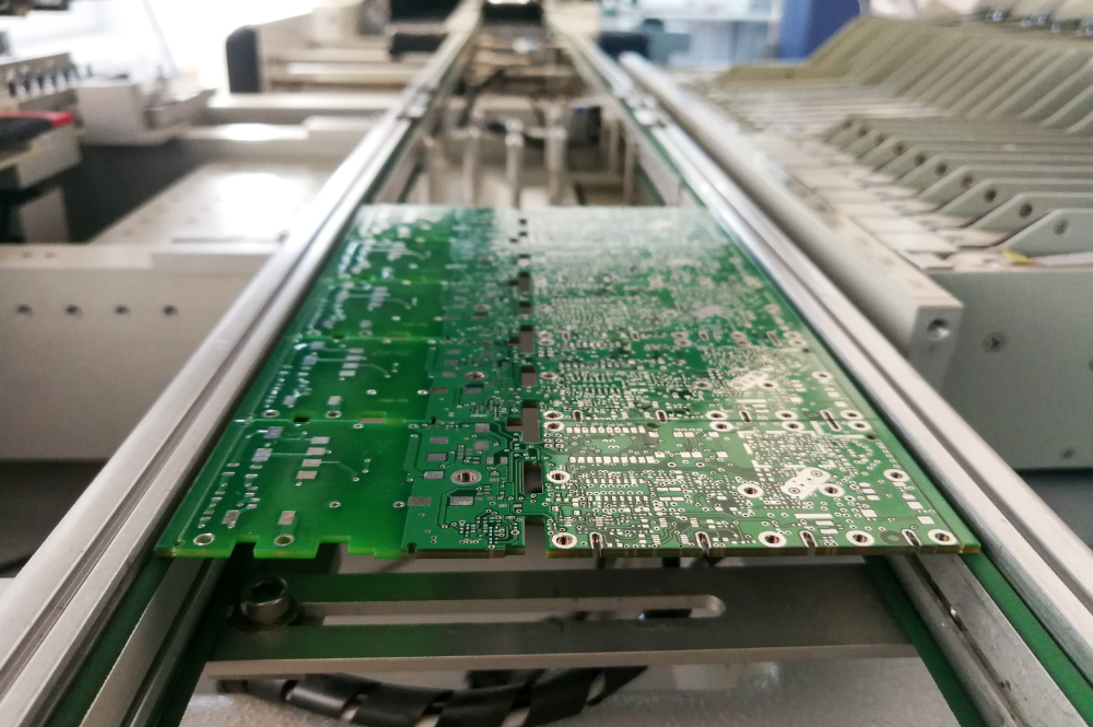 A machine producing electronic components on a conveyor belt, showcasing high-volume PCB assembly in action.