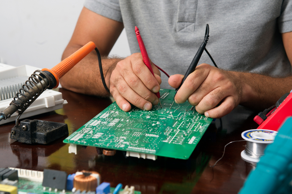 A man working on a circuit board, illustrating PCB design services in action.